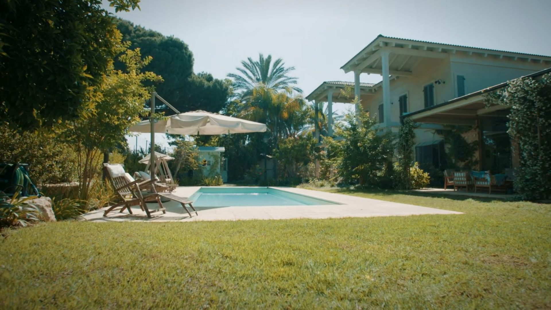 Version 4 film still: a villa garden with a pool